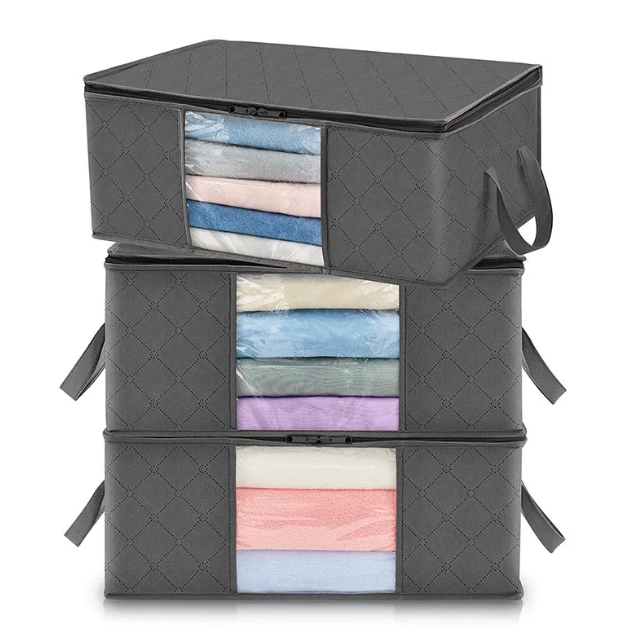 Stack of gray storage bins with transparent panels showing folded clothes inside on a white background
