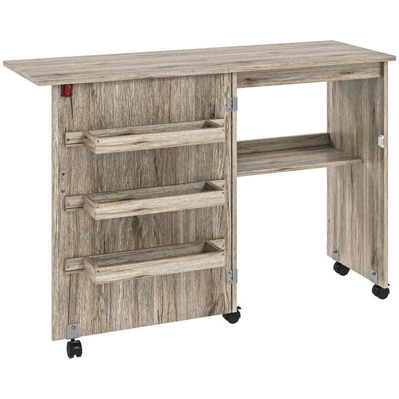 Grey wood-effect folding sewing table with drop leaf, three storage bins, open shelf and wheels