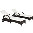 Pair of brown rattan sun loungers with cream cushions and a glass-top side table