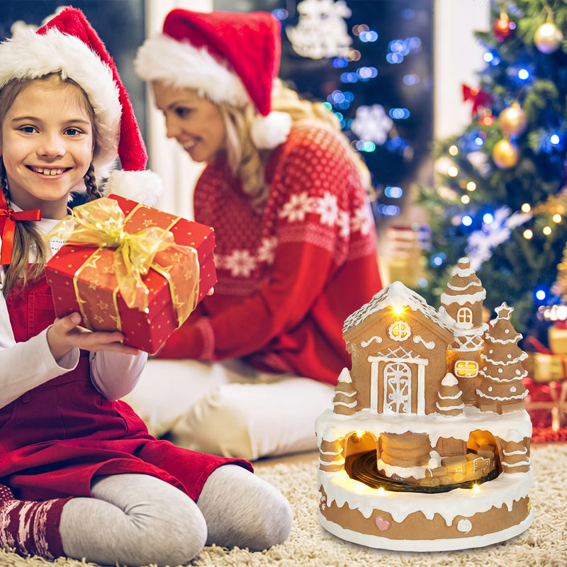 Light-up gingerbread house Christmas decoration displayed beside a Christmas tree and gifts