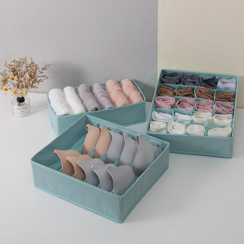 Teal underwear organizer with neatly folded pairs of underwear on a light gray surface.