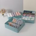 Teal underwear organizer with neatly folded pairs of underwear on a light gray surface.