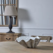 Shell bowl on a wooden table beside a lamp