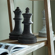 Charcoal grey king and queen chess pieces on a wooden shelf, other pieces sold separately