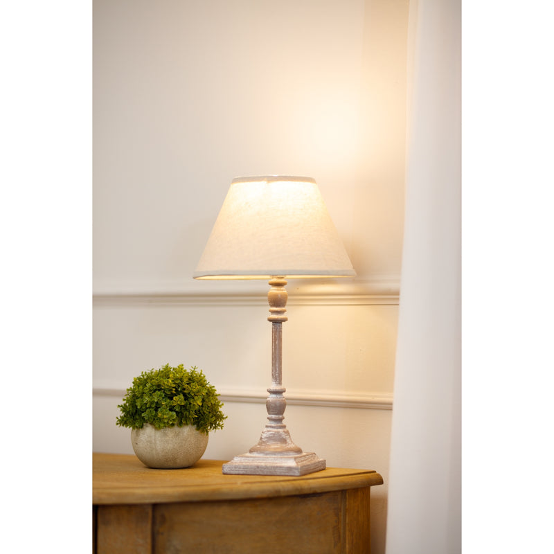 Antia table lamp lit on a wooden sideboard with a small plant