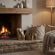 Antique bronze log and kindling buckets beside a lit fireplace