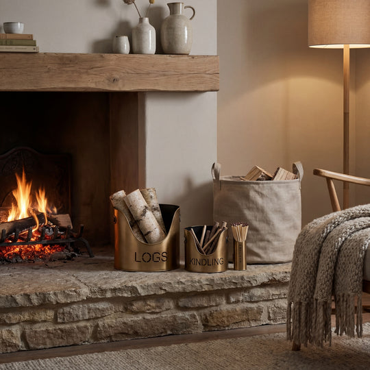 Antique bronze log and kindling buckets beside a lit fireplace