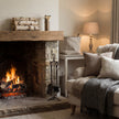 Bronze match holder on a rustic mantel above a lit fireplace