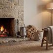 Pewter coal bucket beside a lit stone fireplace