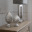 Silver pinecone finials on a wooden sideboard, shown with a taller size sold separately