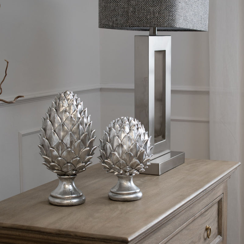 Silver pinecone finials on a wooden sideboard, shown with a taller size sold separately