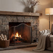 Antiqued silver fire screen in front of a lit stone fireplace