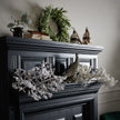 Snowy branches laid along a black mantelpiece