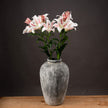 stargazer lilies in a stone vase on a wooden table