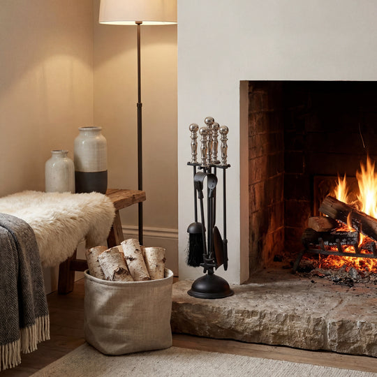 Black and chrome companion set beside a lit fireplace