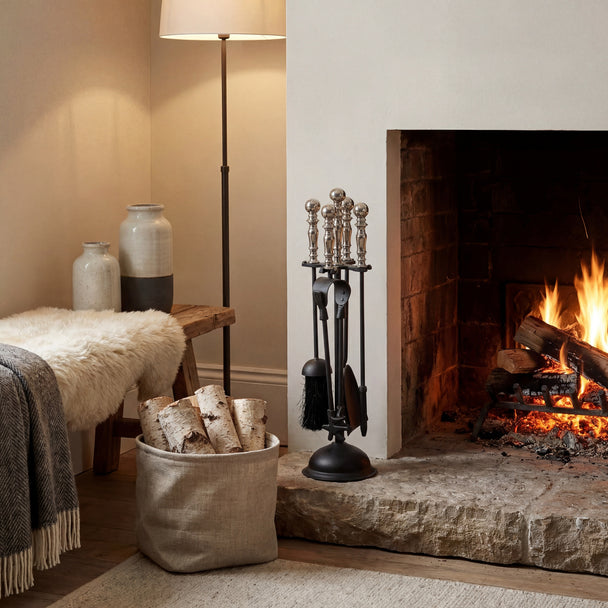 Black and chrome companion set beside a lit fireplace