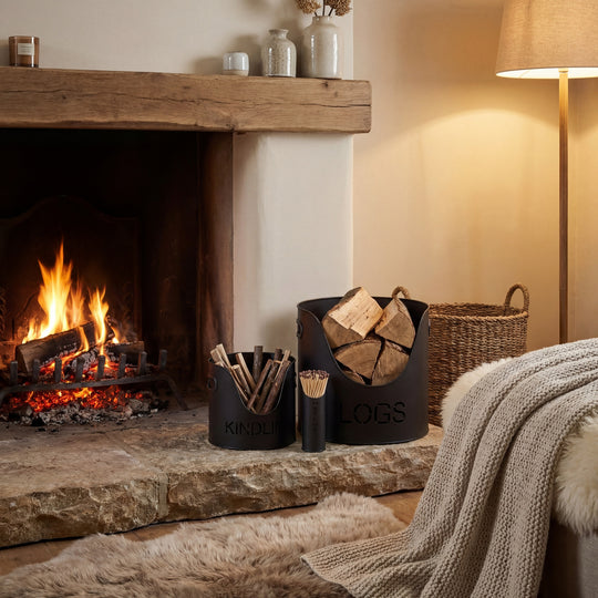 Black log and kindling buckets beside a lit fireplace