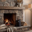 Black coal bucket next to a lit stone fireplace