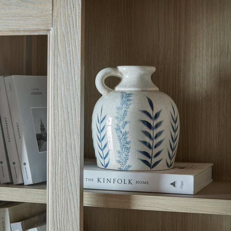 Blue Flora jug vase on a wooden shelf with books
