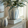 Blue leaf pattern vase with greenery on a painted cabinet