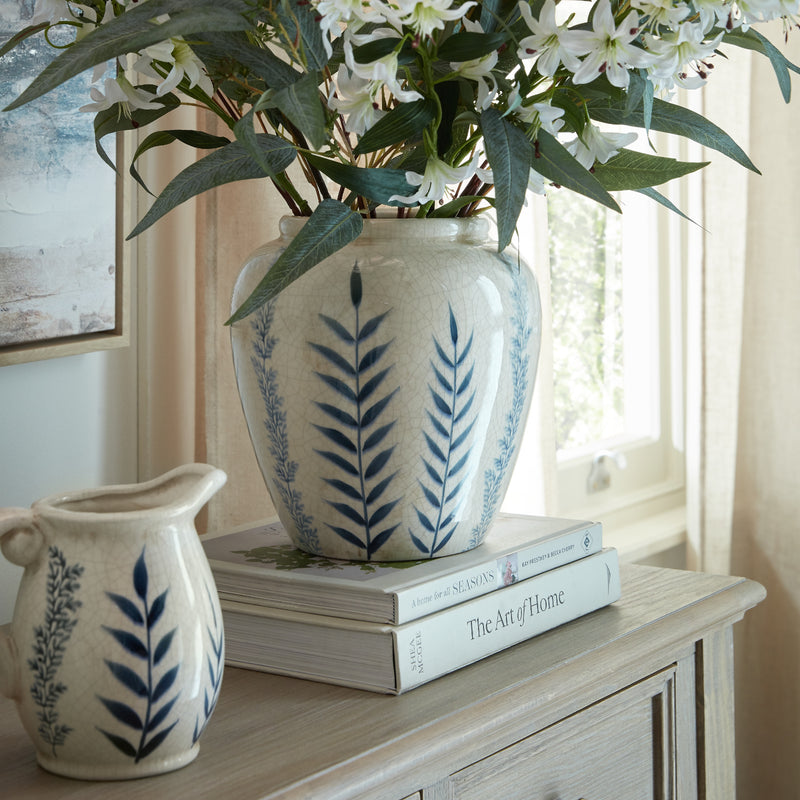 Blue leaf pattern vase with greenery on a painted cabinet