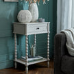 Camden side table beside a sofa with vases