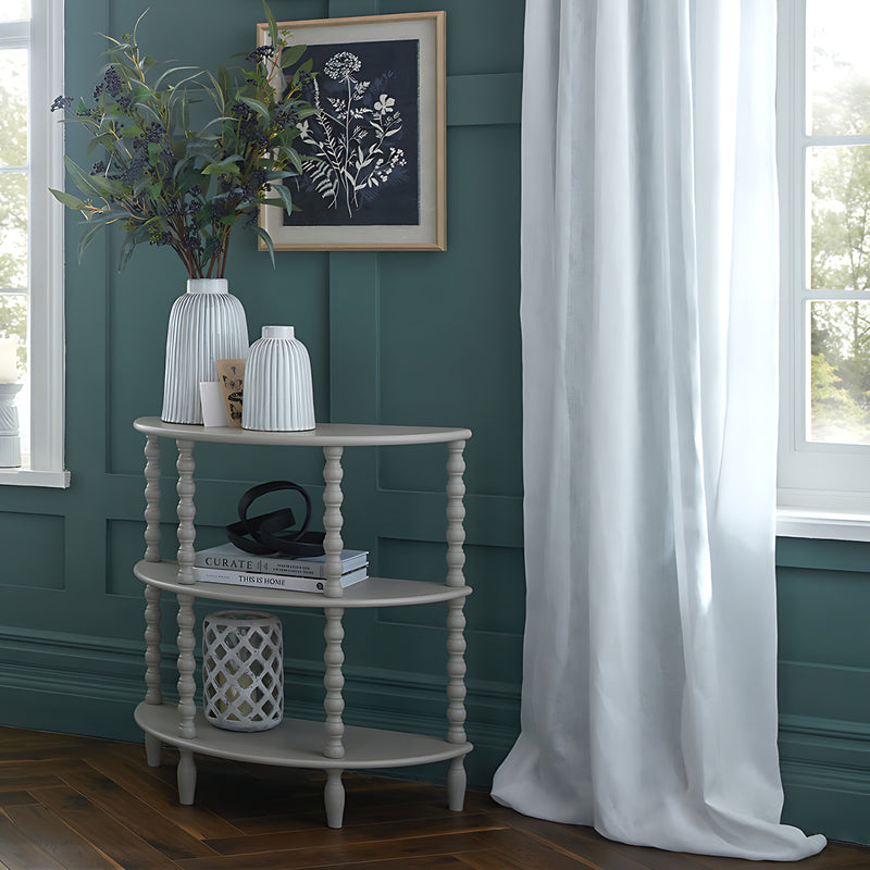 Half moon tier table styled with vases against a teal wall