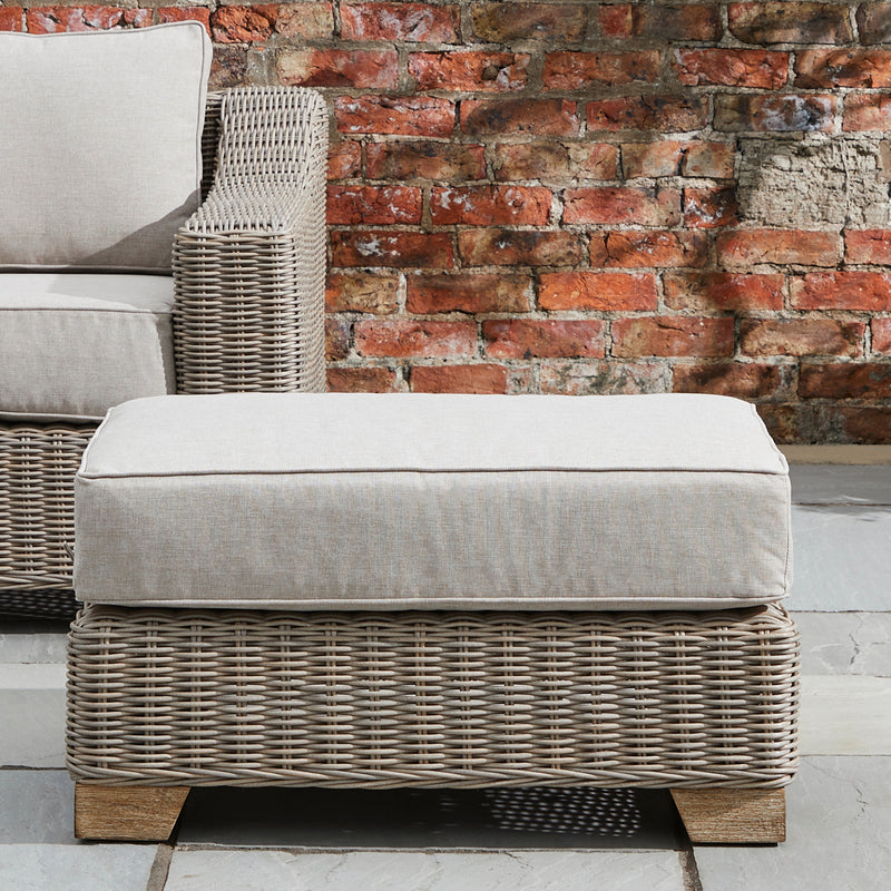 Capri footstool on a patio beside a wicker armchair