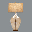 Glass table lamp switched on against a grey background