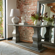 Woman's head bust on a grey console table against a brick wall