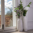 Close view of Darcy Ople vases with faux stems by a window