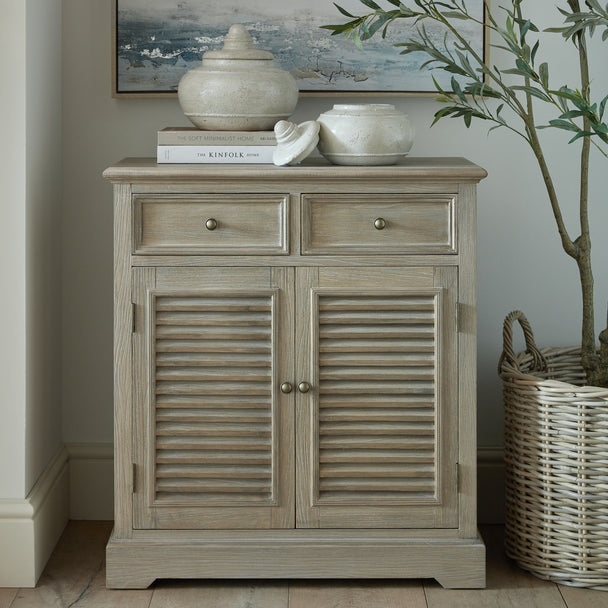 Delphine chest in a bedroom with a lamp, vases and a basket