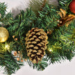 Close-up of a pine cone and lights on the wreath