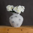 Downton vase filled with white hydrangeas on a wooden table
