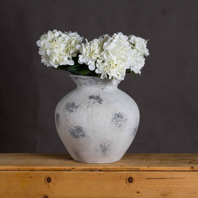 Downton vase filled with white hydrangeas on a wooden table