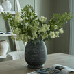 Etched tall vase filled with green hydrangeas on a dining table