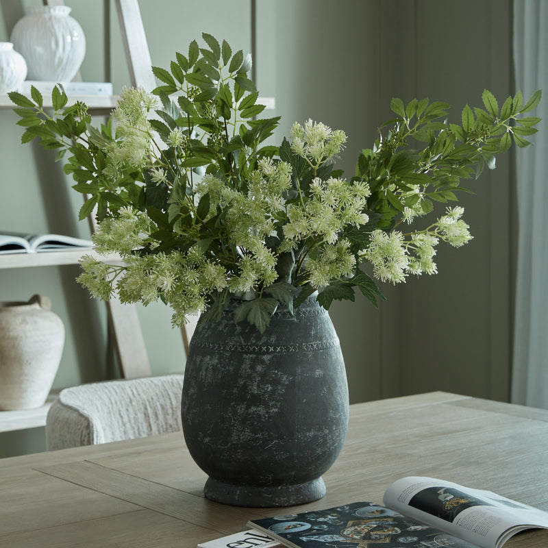 Etched tall vase filled with green hydrangeas on a dining table