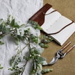 Winter garland laid on a table beside a notebook and secateurs