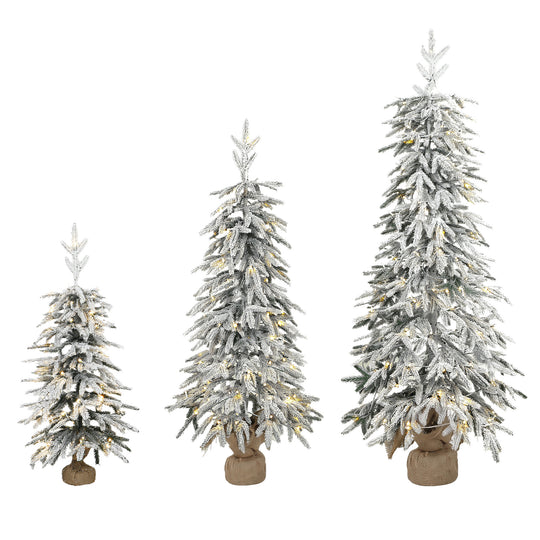 Set of three snow-flocked pre-lit pencil Christmas trees with warm white LEDs on fabric-wrapped bases