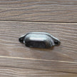 close-up of a dark metal cup handle on the wood grain