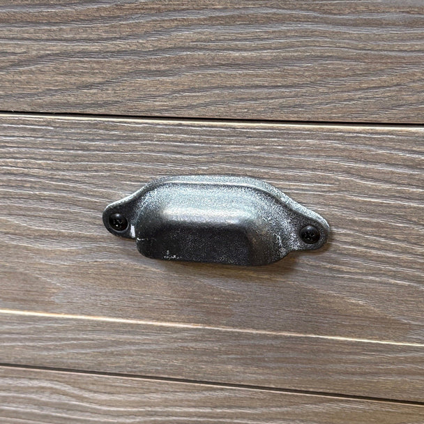 close-up of a dark metal cup handle on the wood grain