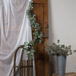 Winter garland draped over a rustic wooden door beside a chair