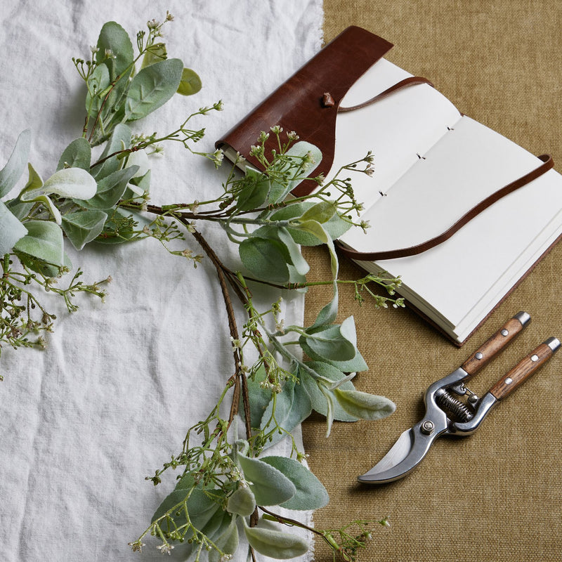 Lamb's ear garland on a table with a notebook and secateurs