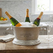Antique pewter champagne cooler filled with ice and bottles on a kitchen table