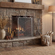 Antique silver ornate fire screen in front of a lit stone fireplace