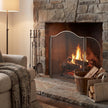 Large antiqued silver fire screen in front of a lit stone fireplace