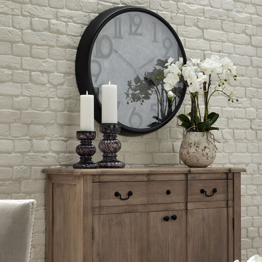 white orchid on a wooden sideboard below a wall clock