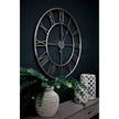 Silver skeleton clock on a dark wall above a sideboard