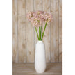 lilac alliums in a tall white vase against a wooden wall