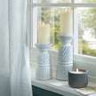 White carved candle holders with pillar candles on a windowsill